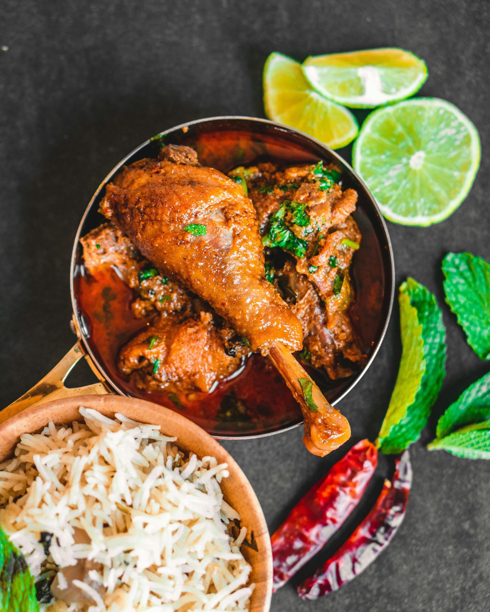 Delicious Indian chicken curry served with basmati rice, garnished with limes and mint leaves.